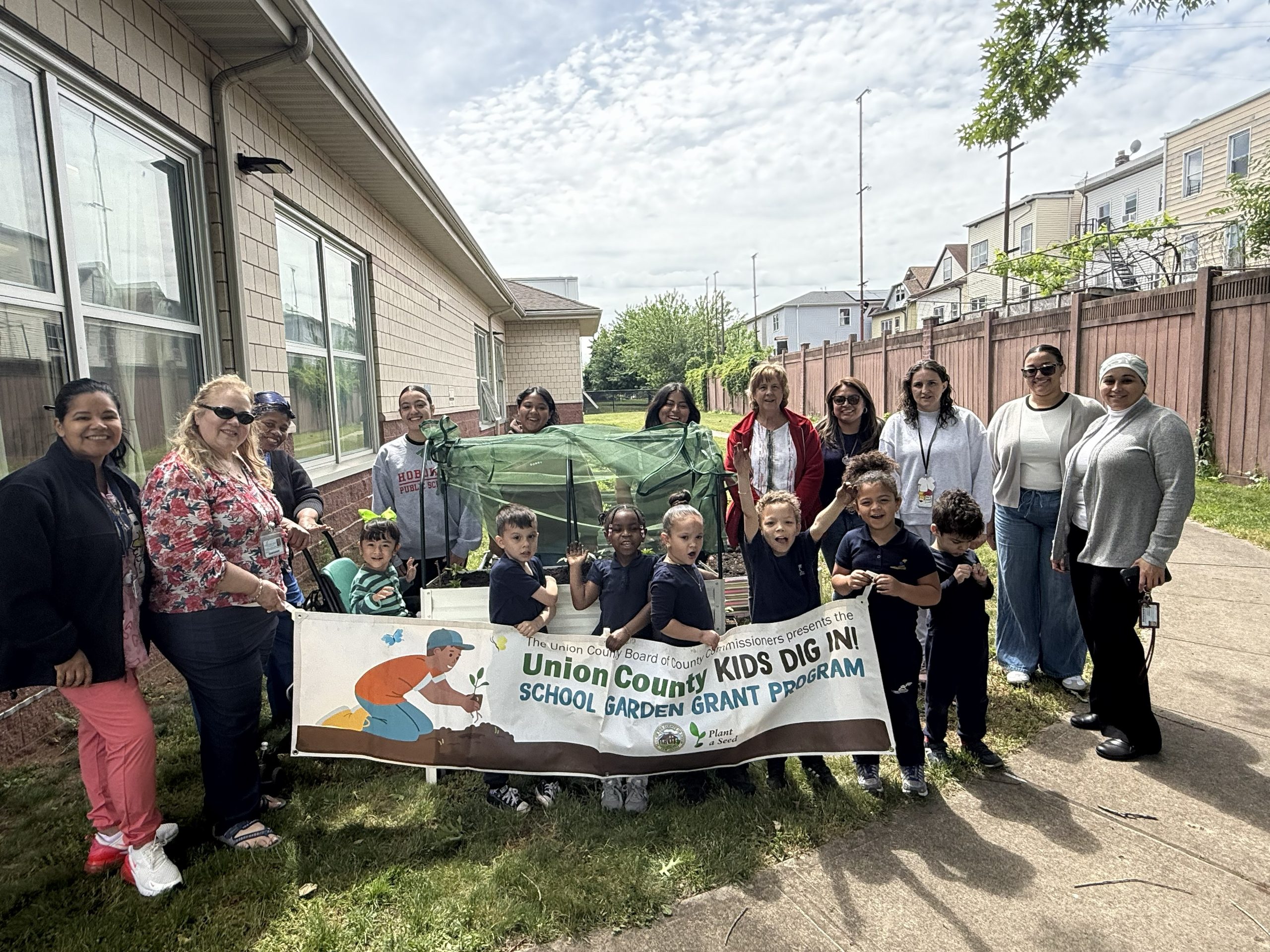 School No. 52 students, teachers and Groundwork Elizabeth staff pose for a picture holding up their Kids Dig In Garden Grant banner