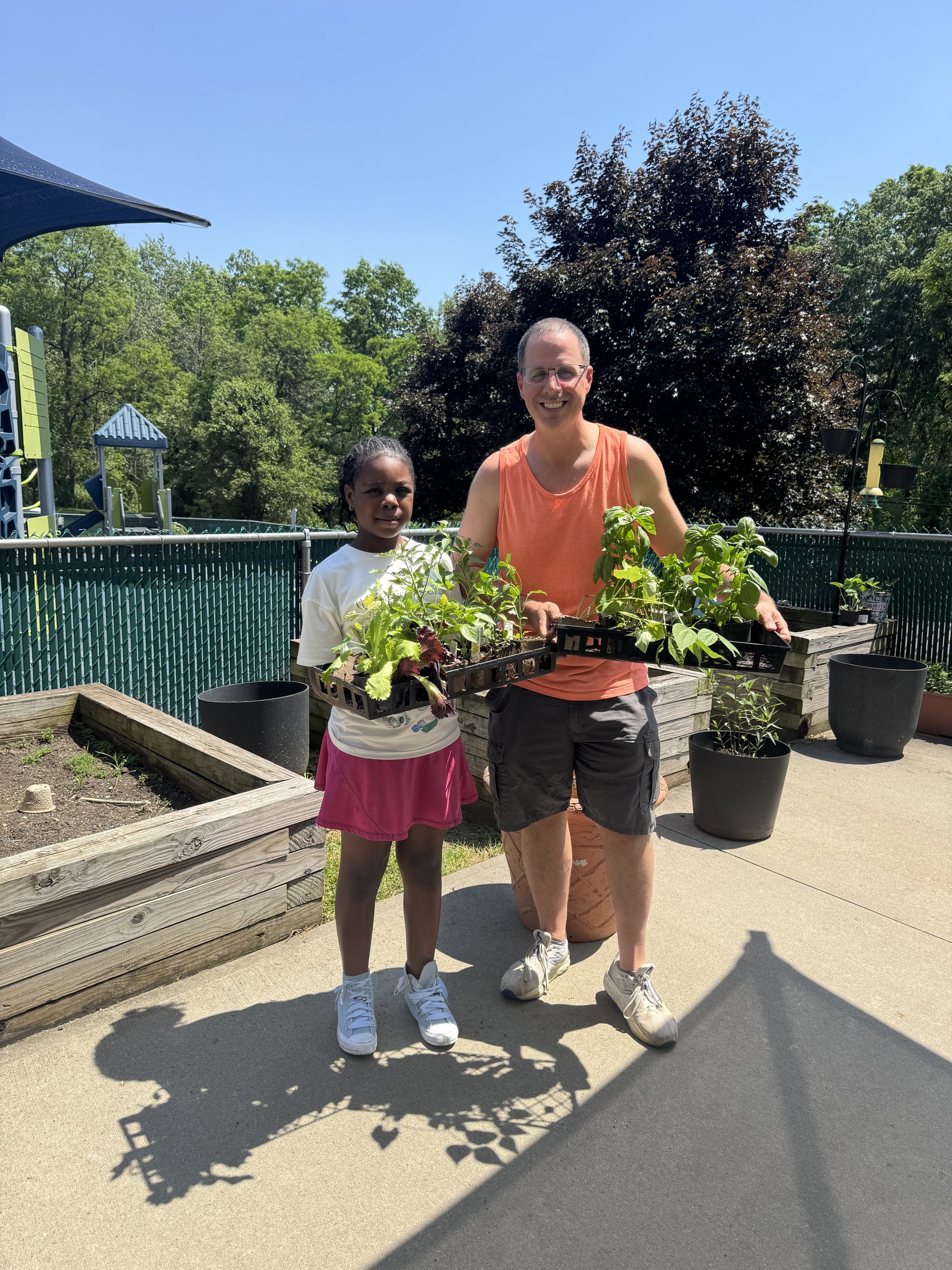 Image of teacher and female student holding several plant starters in their hands