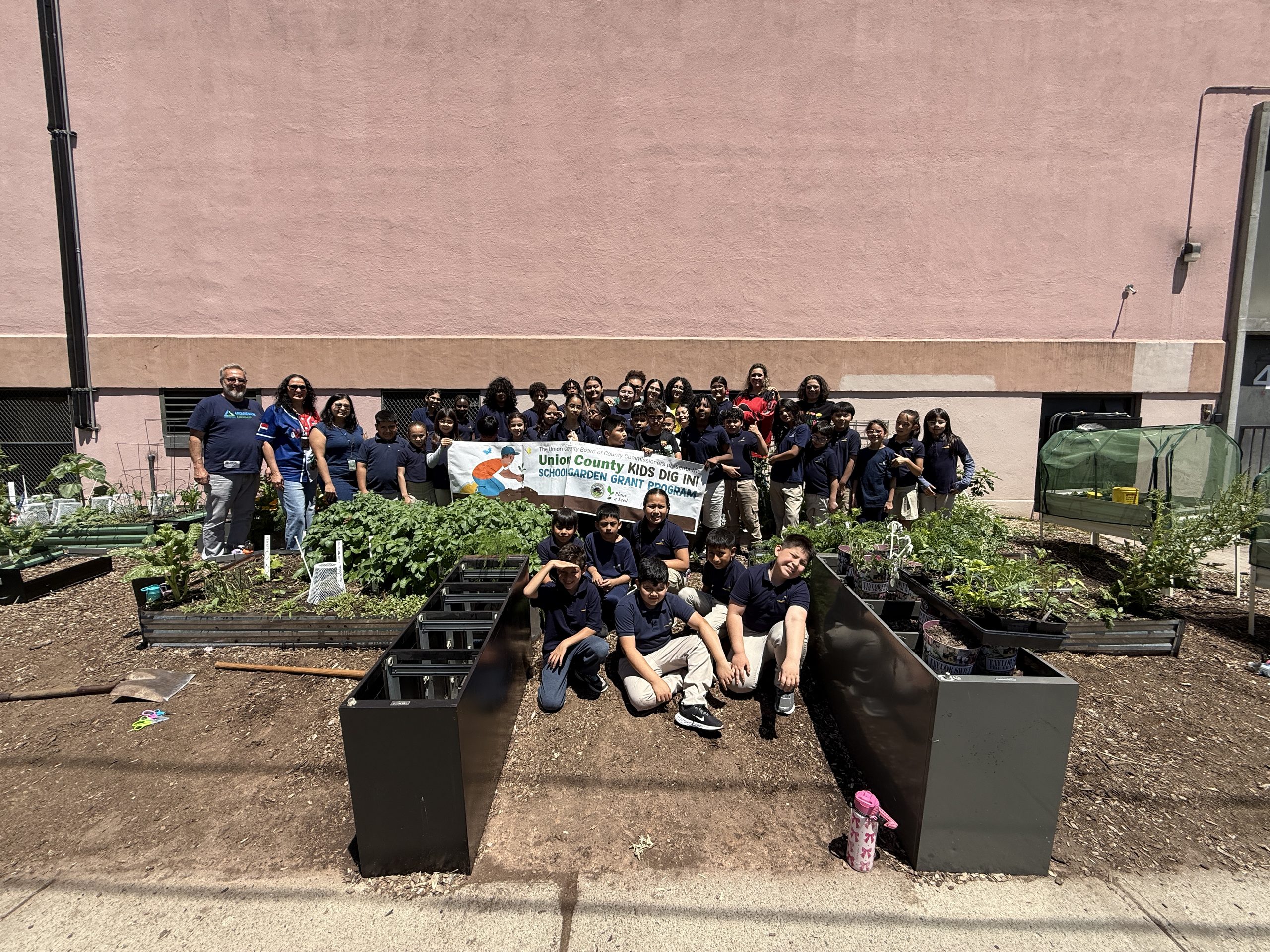 School No. 12 students, faculty, and Union County representatives pose with the Kids Dig In Garden Grant Banner 
