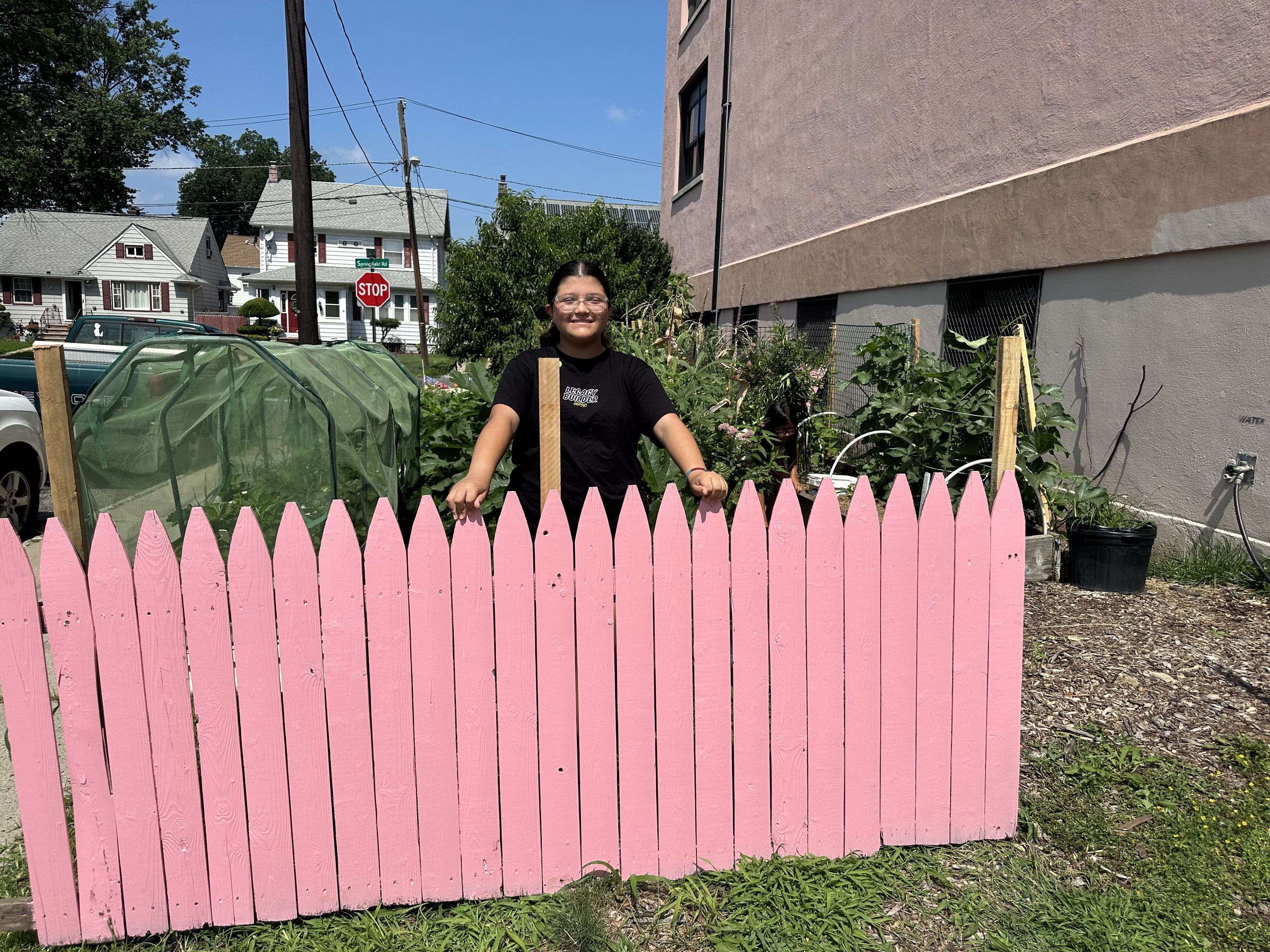 School No. 12 female student standing behind wooden pink fence
