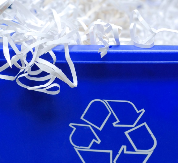 blue recycle bin with shredded paper spilling out