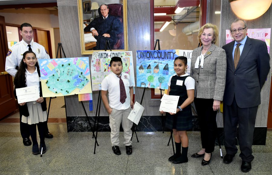 Three fourth grade students presenting their contest winning artwork 