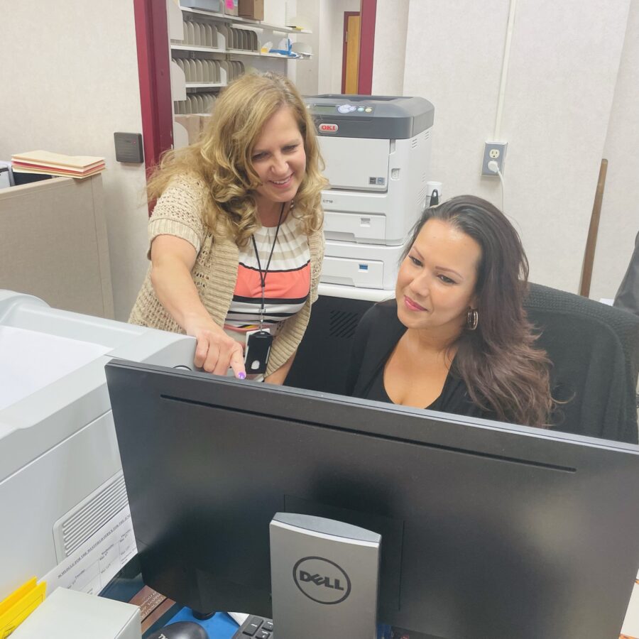 Two women discussing what is on a computer moniter