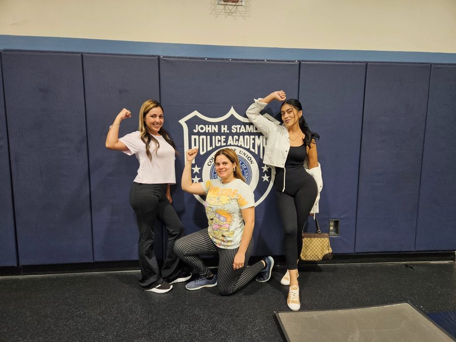 Image of three women flexing their arm muscles at a previous "Empower & Protect" self-defense class
